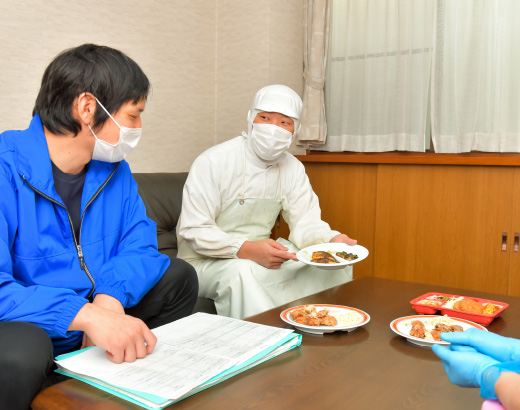 机に食品を並べて打ち合わせする勇輝フーズ長浜のスタッフ